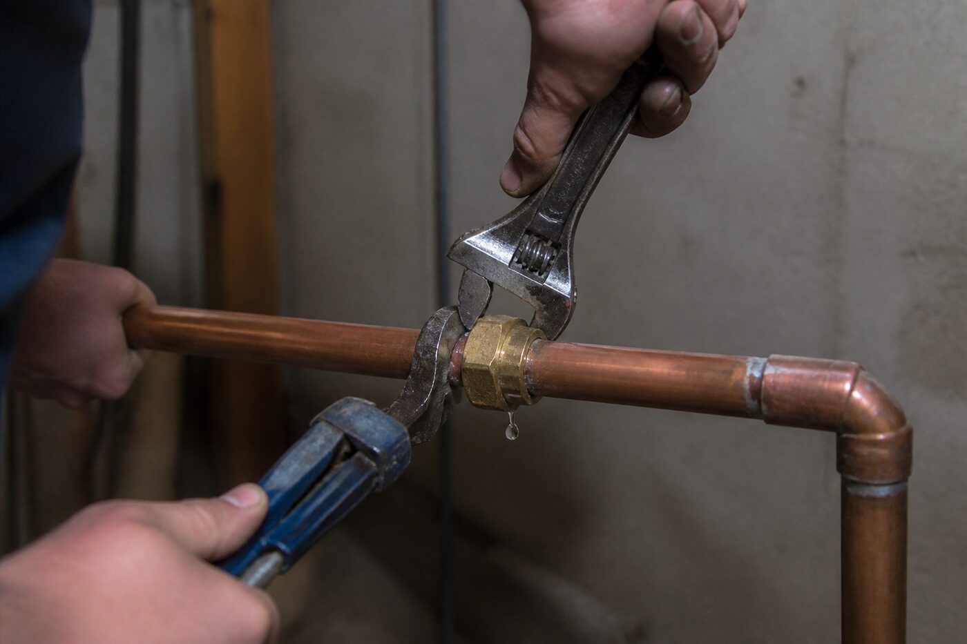 Copper pipe leak being repaired with wrenches